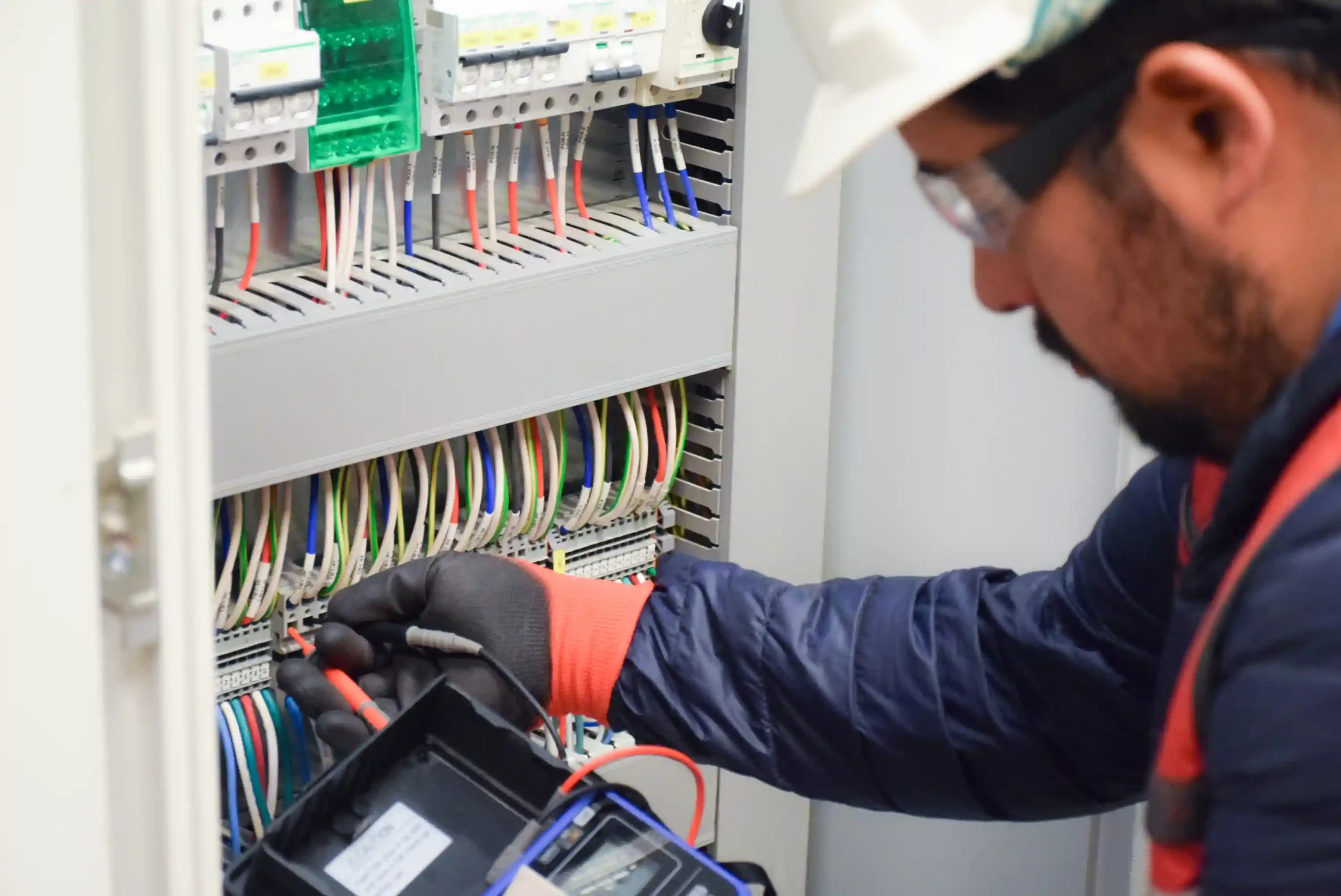 Técnico realizando ajustes y verificaciones en la instalación de tableros eléctricos, utilizando un multímetro para asegurar la correcta conexión de los circuitos.